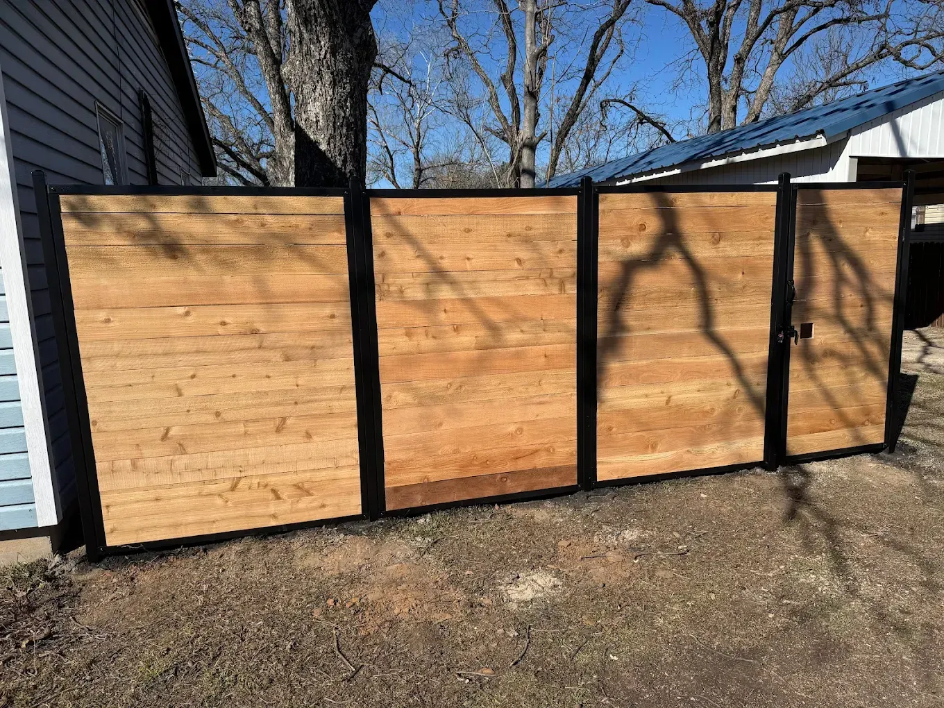 Wooden fence with black frame in a yard.