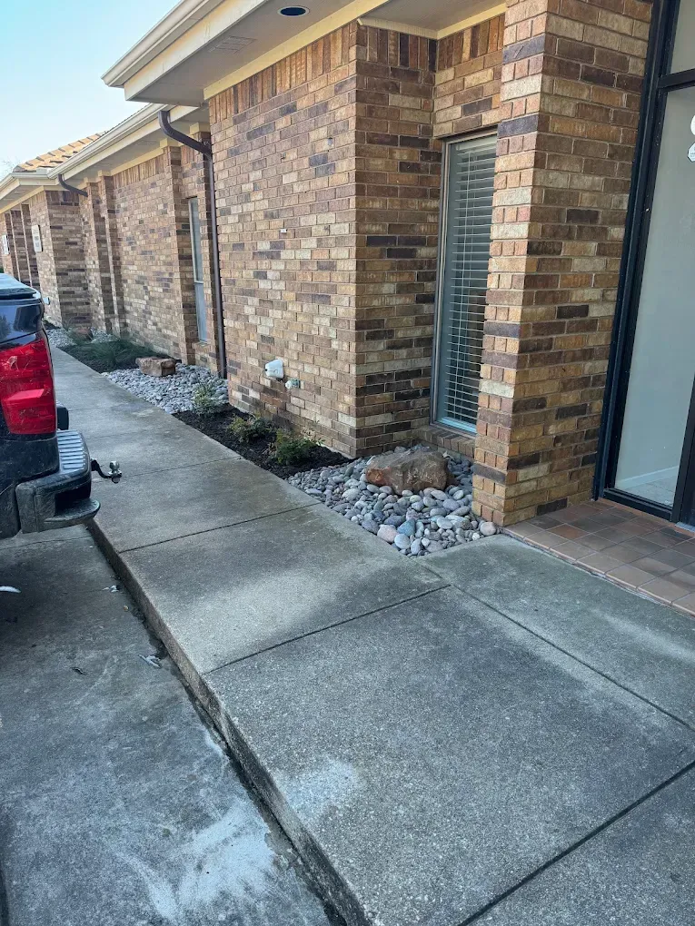 Exterior of building with brick facade and concrete walkway.