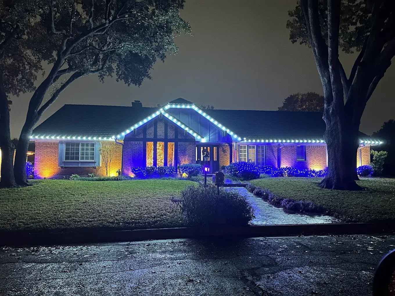 House lit with blue and white Christmas lights at night.