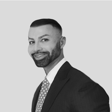 A man in a suit and tie is smiling in a black and white photo.