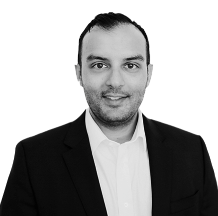 A man in a suit and white shirt is smiling in a black and white photo