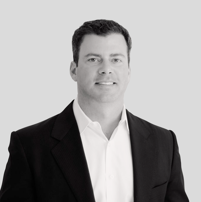 A man in a suit and white shirt is smiling in a black and white photo.