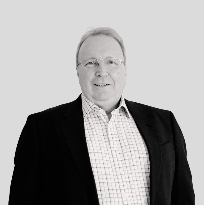 A man in a suit and plaid shirt is smiling in a black and white photo