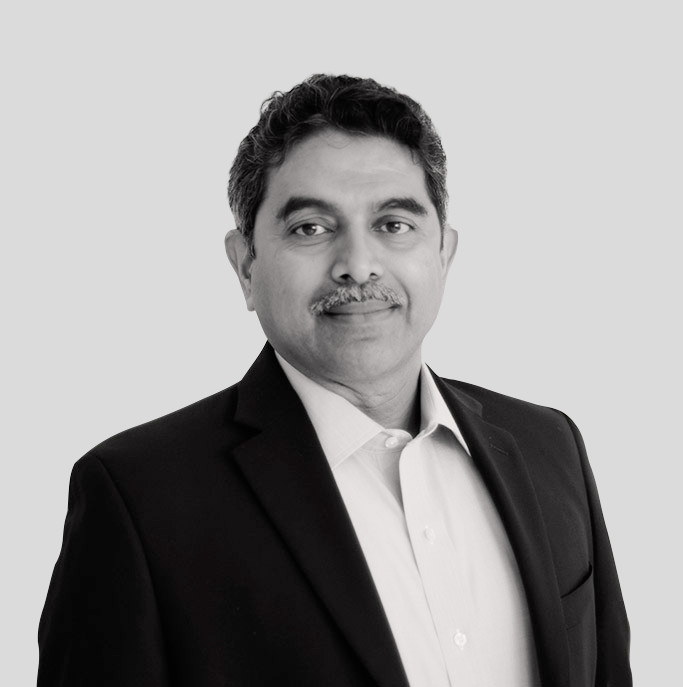 A man in a suit and white shirt is standing in front of a white background.