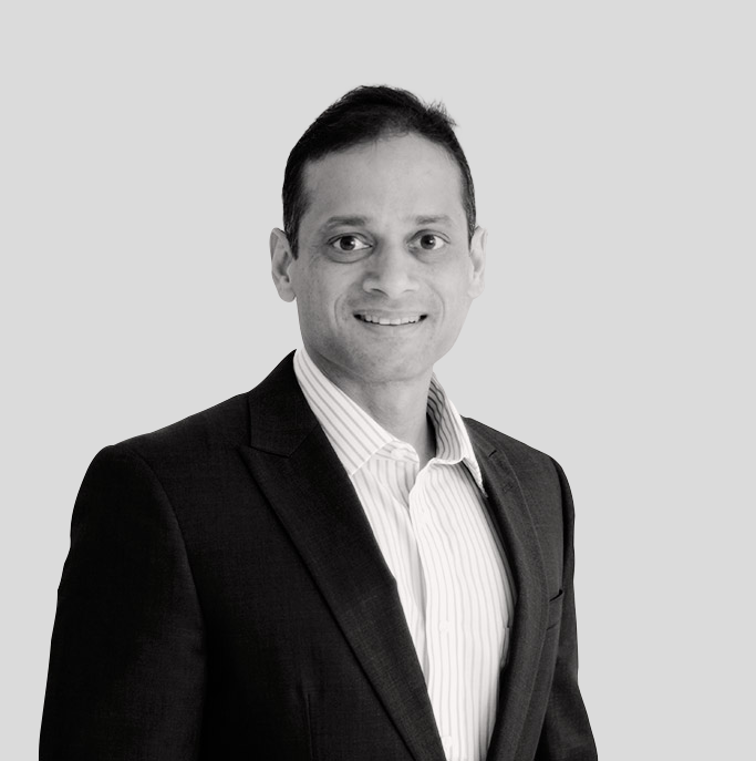 A man in a suit and striped shirt is smiling in a black and white photo.