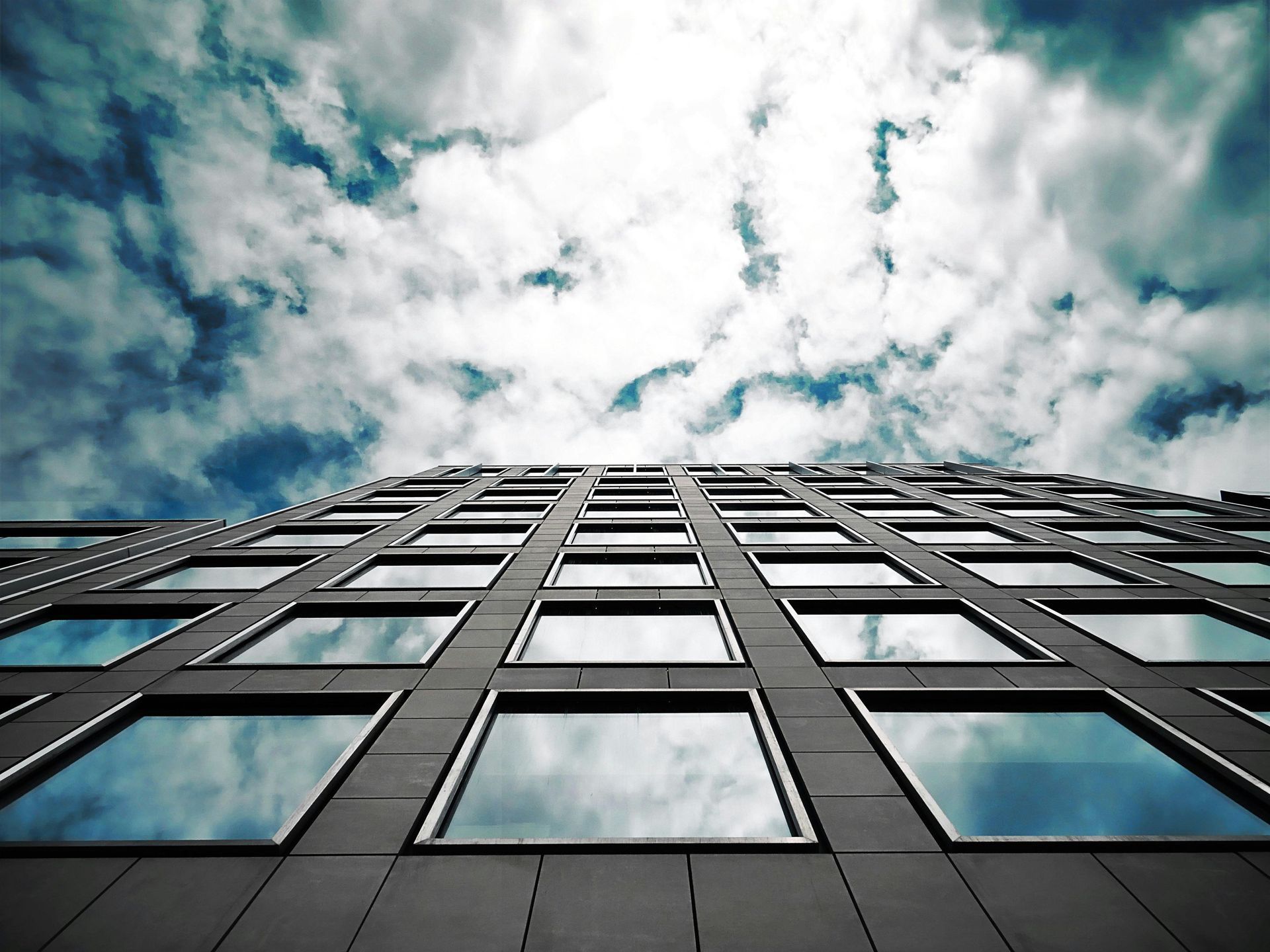 Looking up at a tall building with a cloudy sky in the background