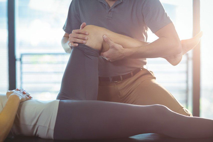 Physiotherapist giving knee therapy to a woman in clinic