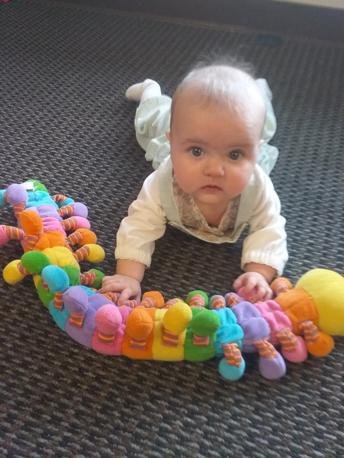 A baby on the floor with a colorful toy in his hands