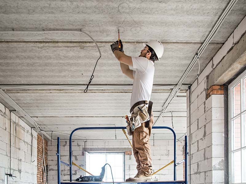 A man is standing on a scaffolding working on a ceiling.