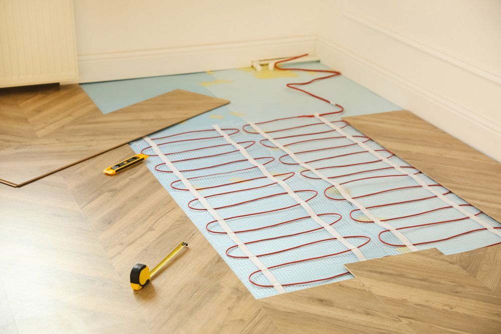 An Electric Floor Heating System is Being Installed on a Wooden Floor — Mark's Flooring & Handyman Services in Doyalson, NSW