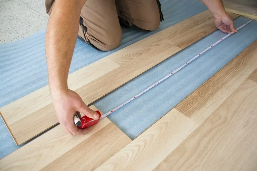 Person Measuring Flooring with a Tape Measure — Mark's Flooring & Handyman Services in Wyong, NSW