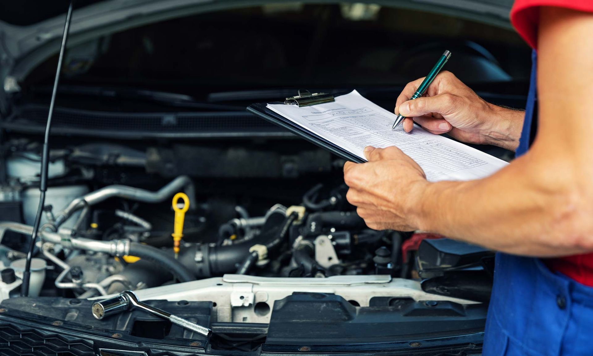 A mechanic is writing on a clipboard while working on a car | Magic Lube & Rubber