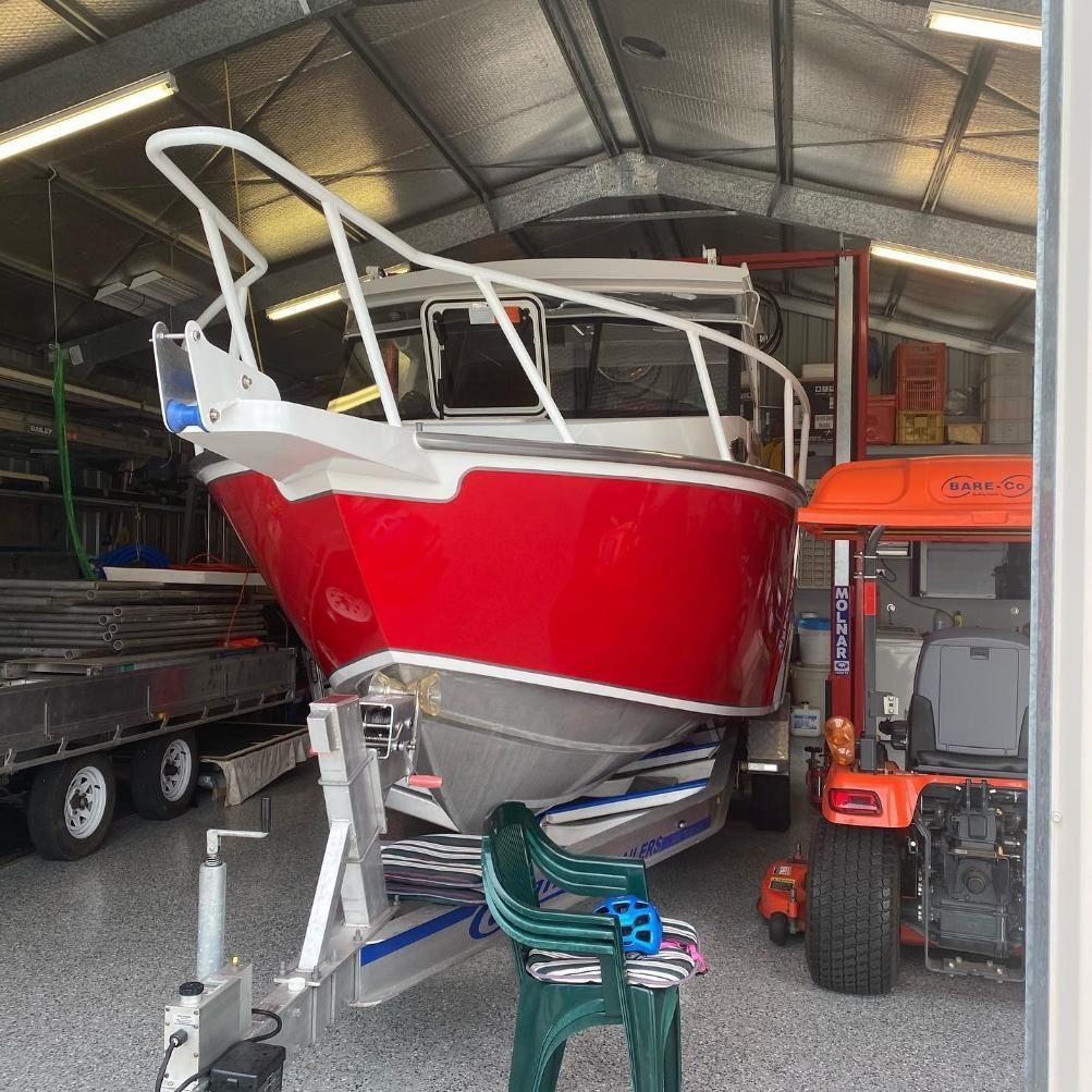 A Red Boat is Sitting on a Trailer in a Garage — Activate Auto Electrics & Air Conditioning In Caloundra, QLD