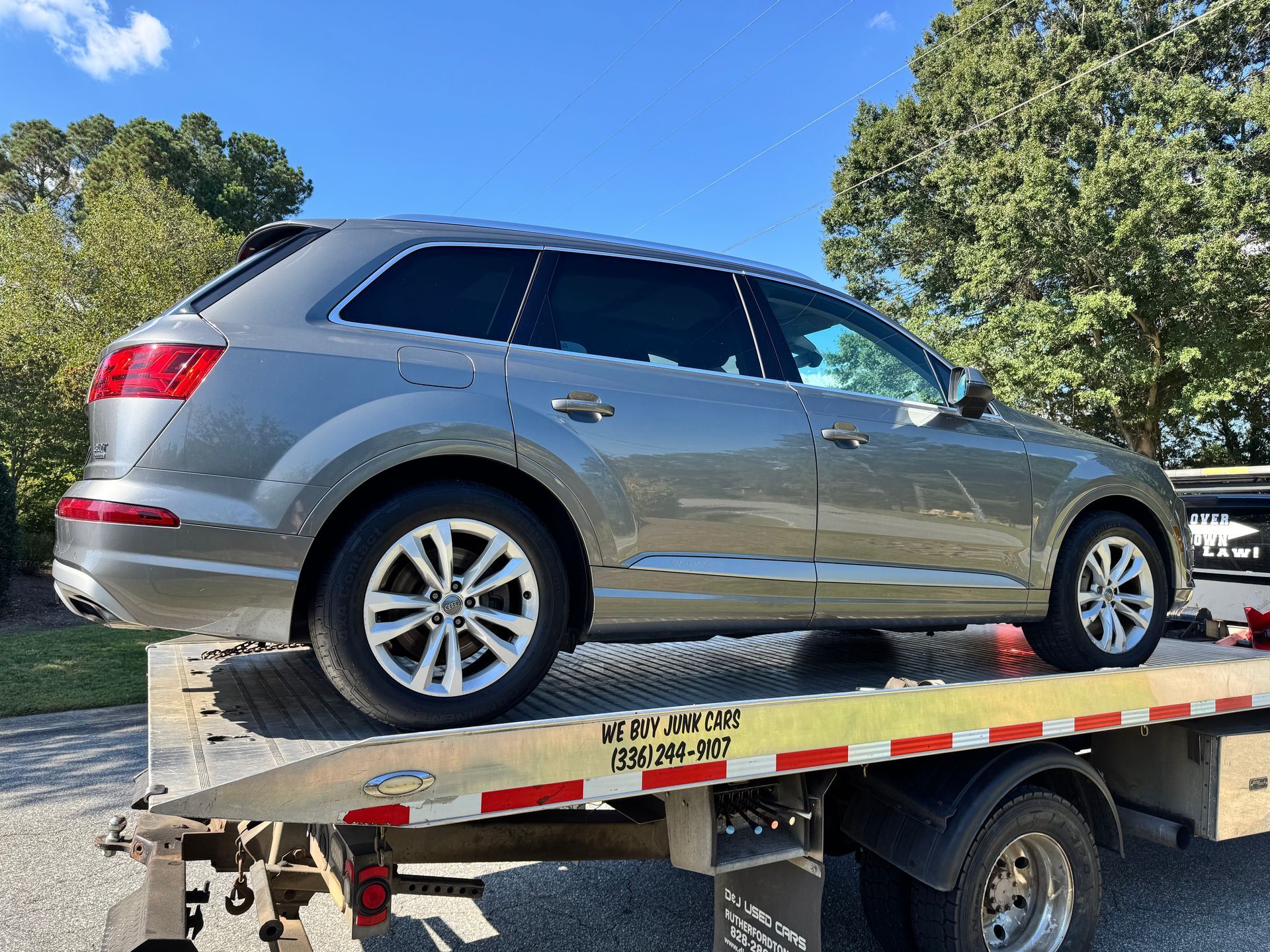 Grey SUV on a tow truck; sunny day.