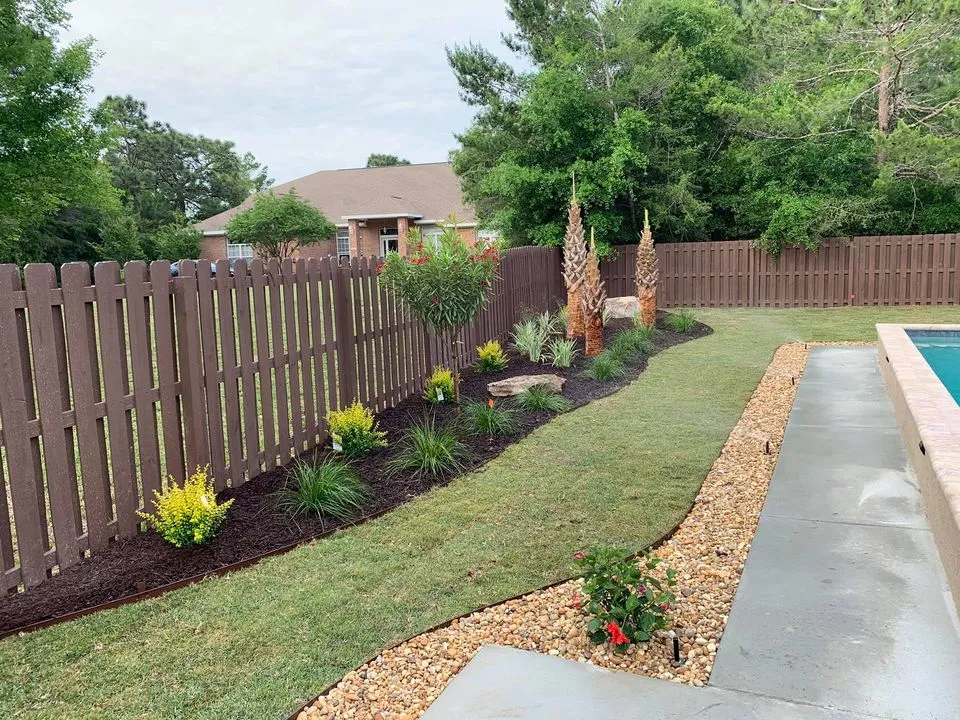 A backyard with a wooden fence and a swimming pool.
