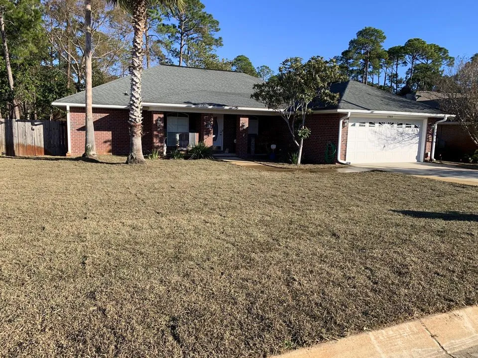 A brick house with a large lawn in front of it.