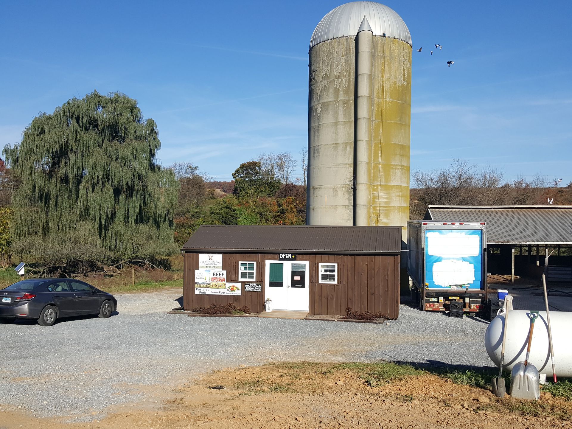 A car is parked in front of a building with a silo in the background