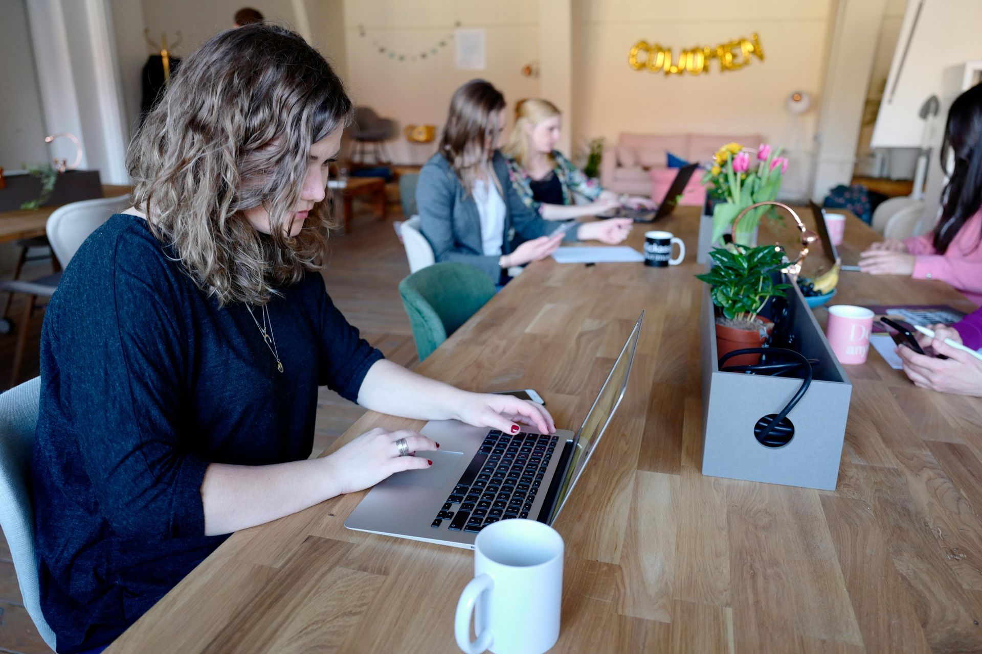 A group of people are sitting at a table using laptops.