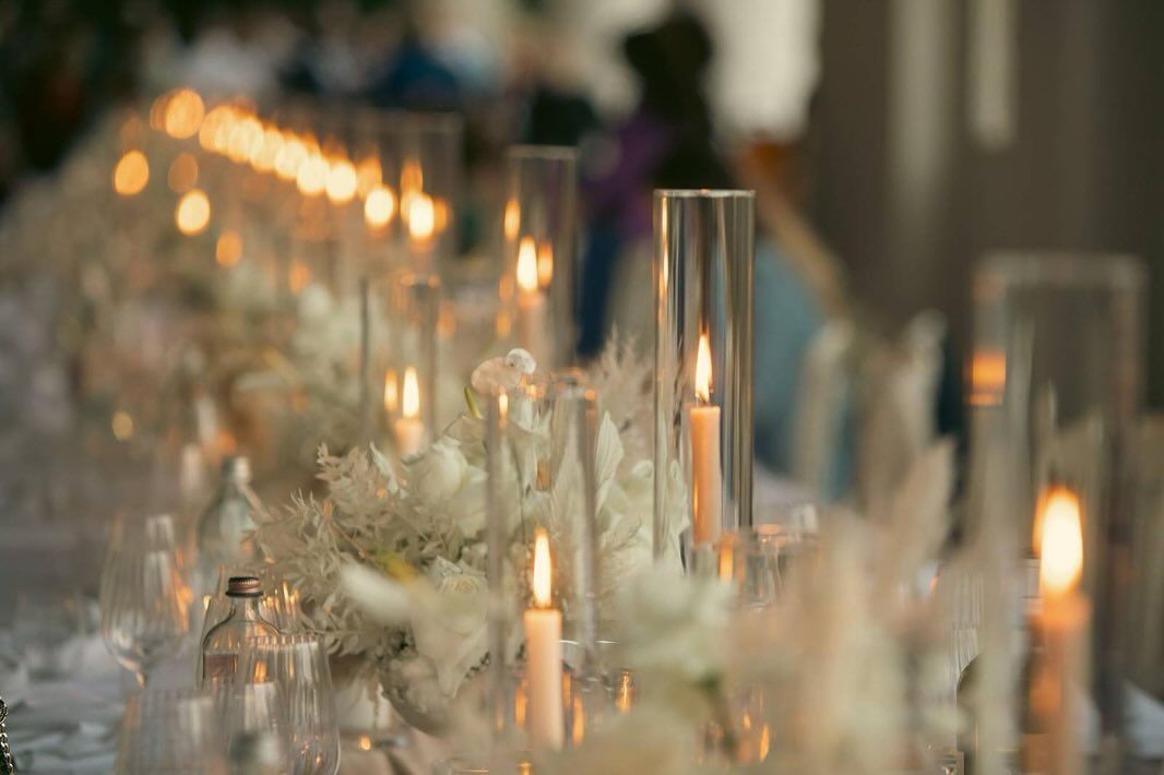 un lungo tavolo con sopra candele e fiori.