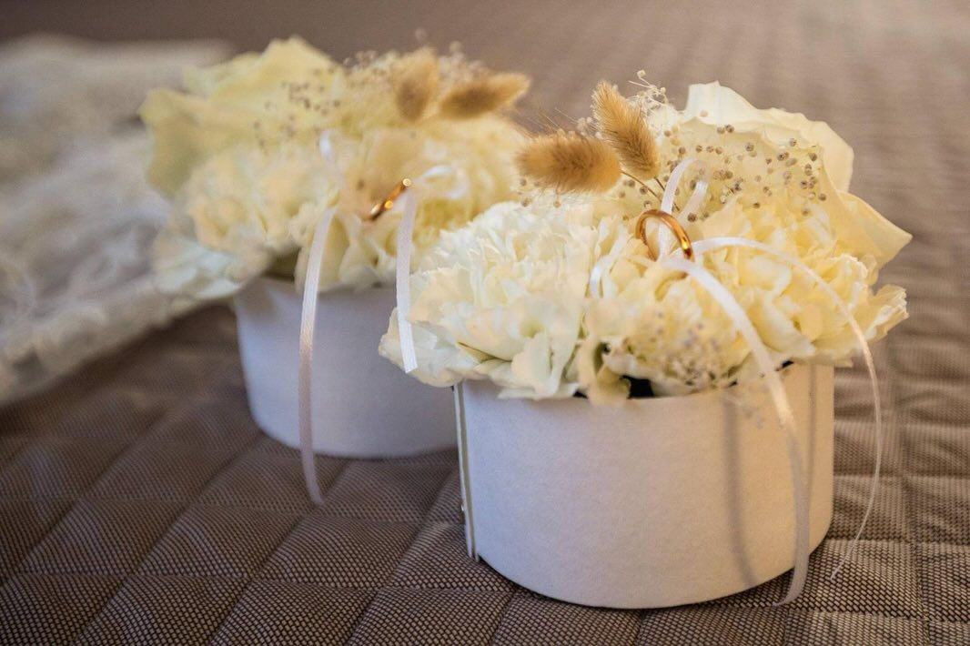 su un tavolo sono sedute due candele piene di fiori e fedi nuziali.