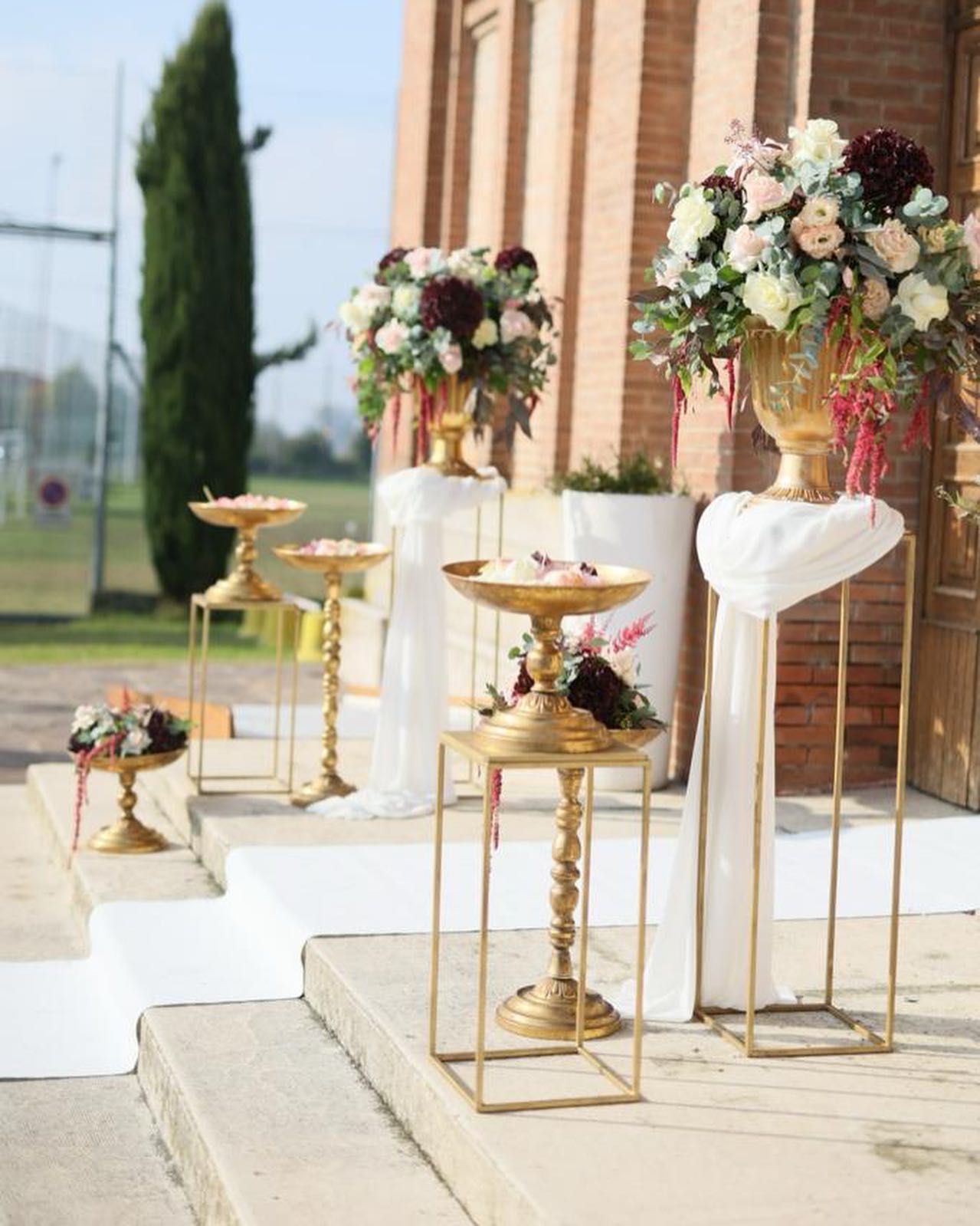 Davanti ad un edificio è allineata una fila di vasi pieni di fiori.