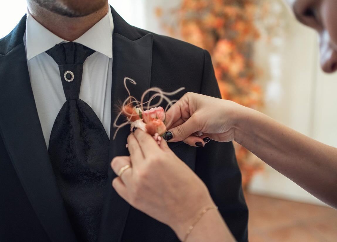 una donna mette un fiore sulla giacca di un uomo.