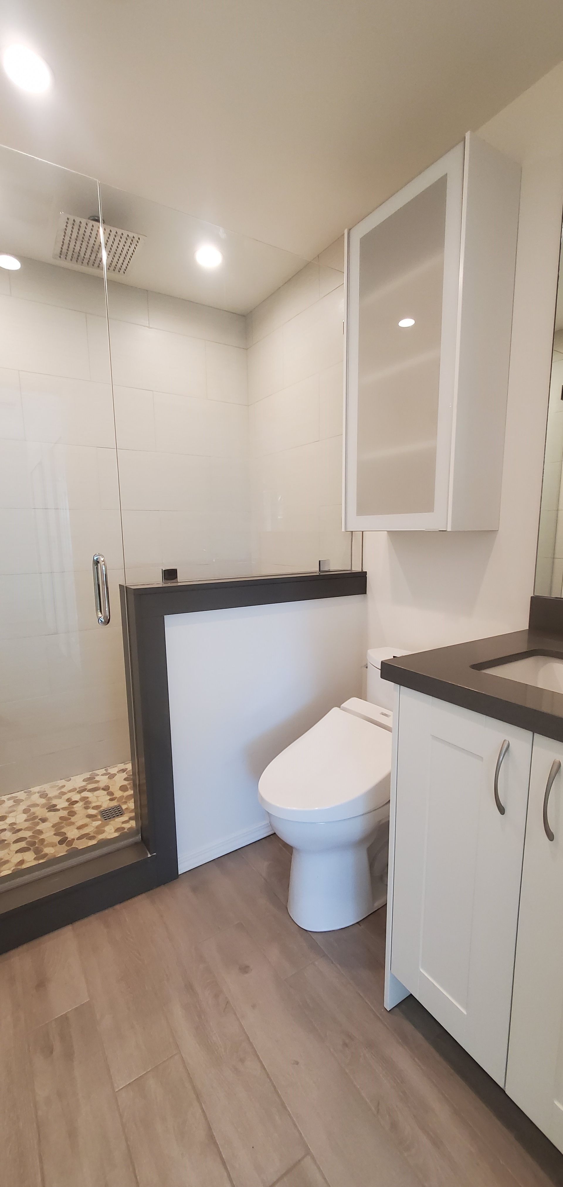 A bathroom with a toilet , sink and shower.