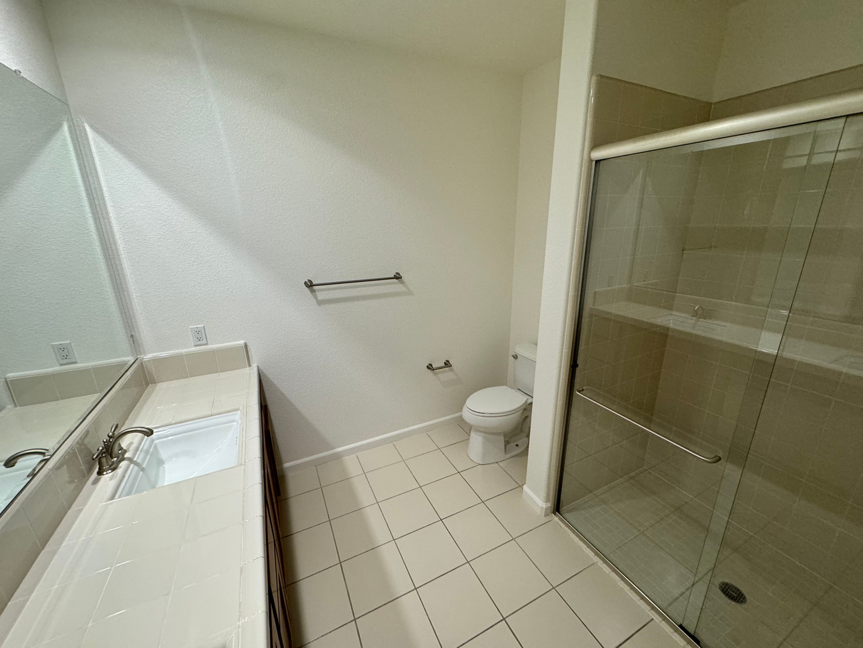 A bathroom with a toilet , sink and shower.