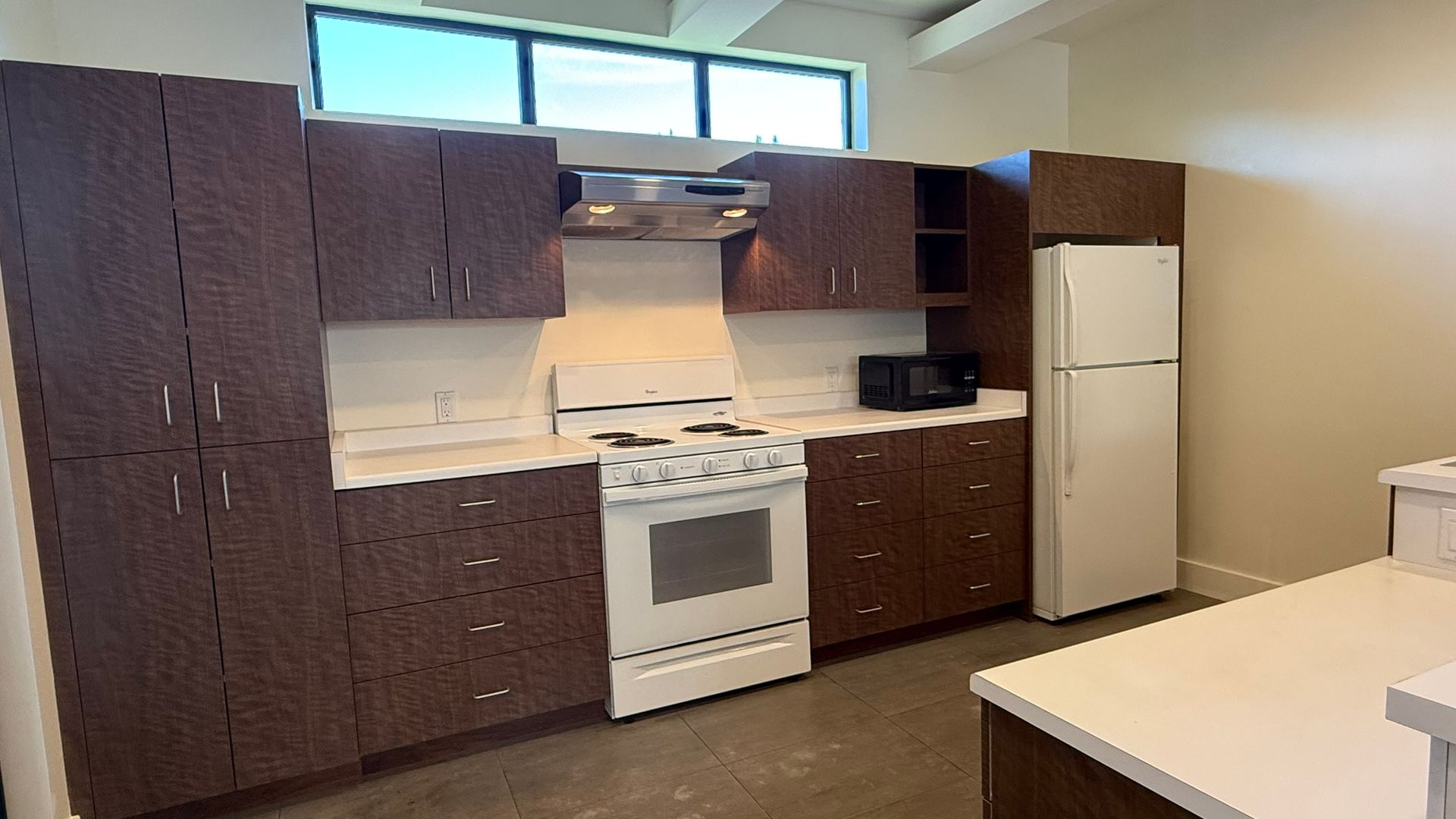 Kitchen with brown cabinets, white appliances, and a window.