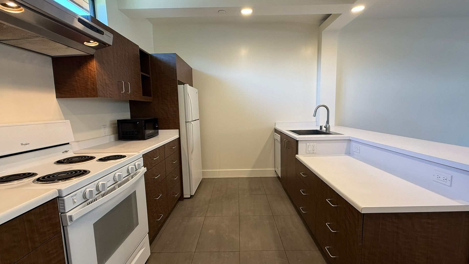 Kitchen with white appliances, dark brown cabinets, and light countertops.