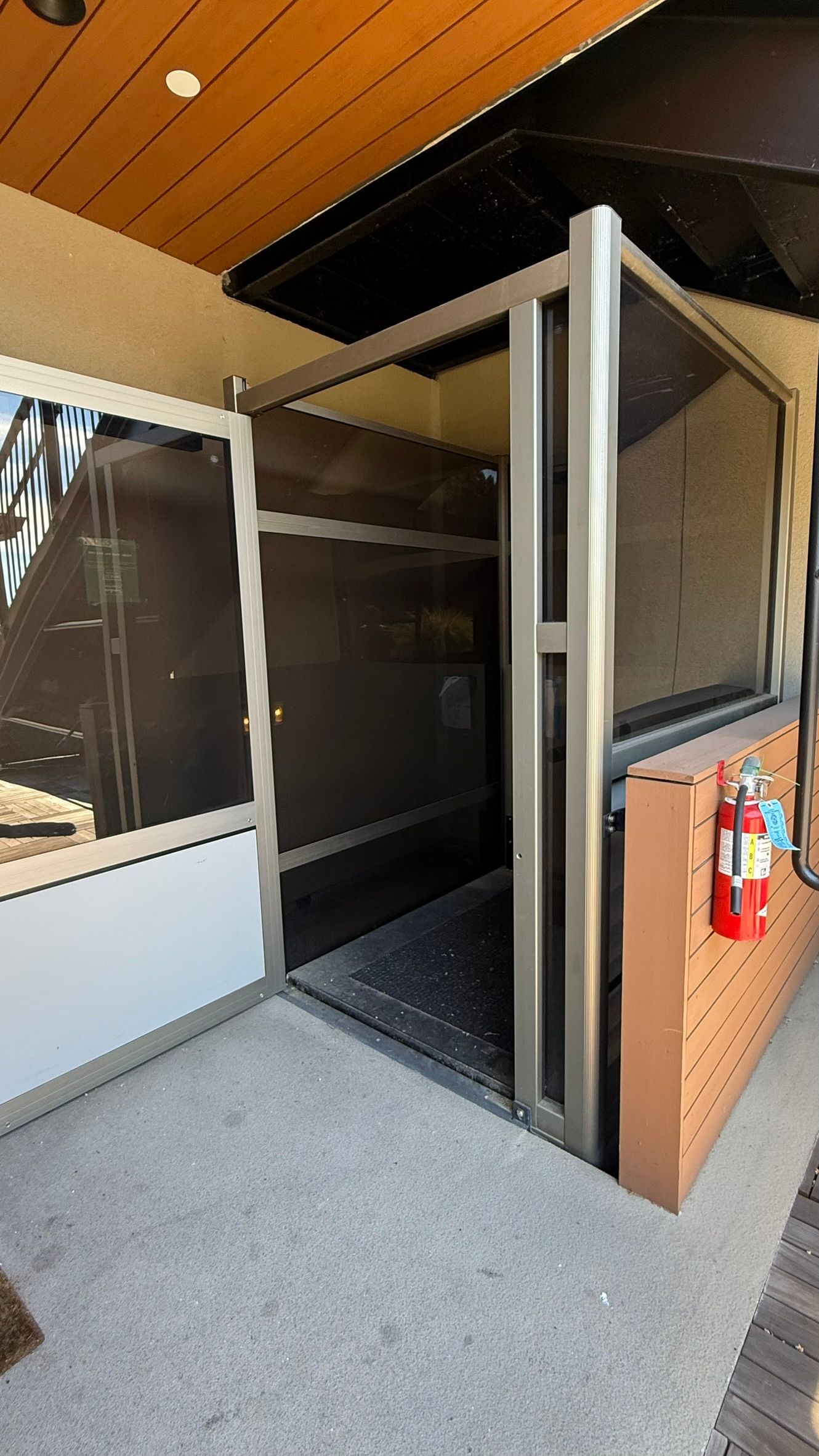 Exterior view of a wheelchair lift with open door, situated beside a building's entrance.