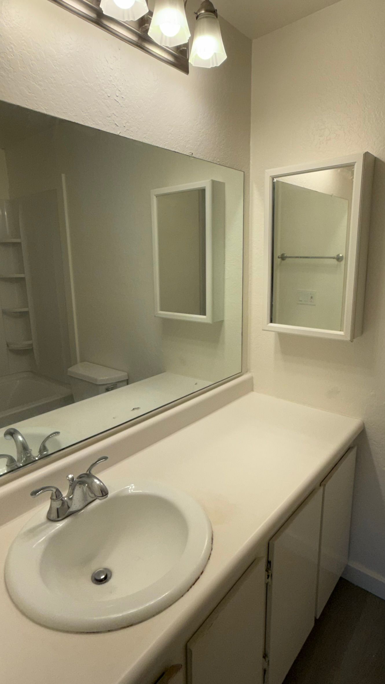Bathroom with white sink, counter, cabinets, mirror, and medicine cabinet.