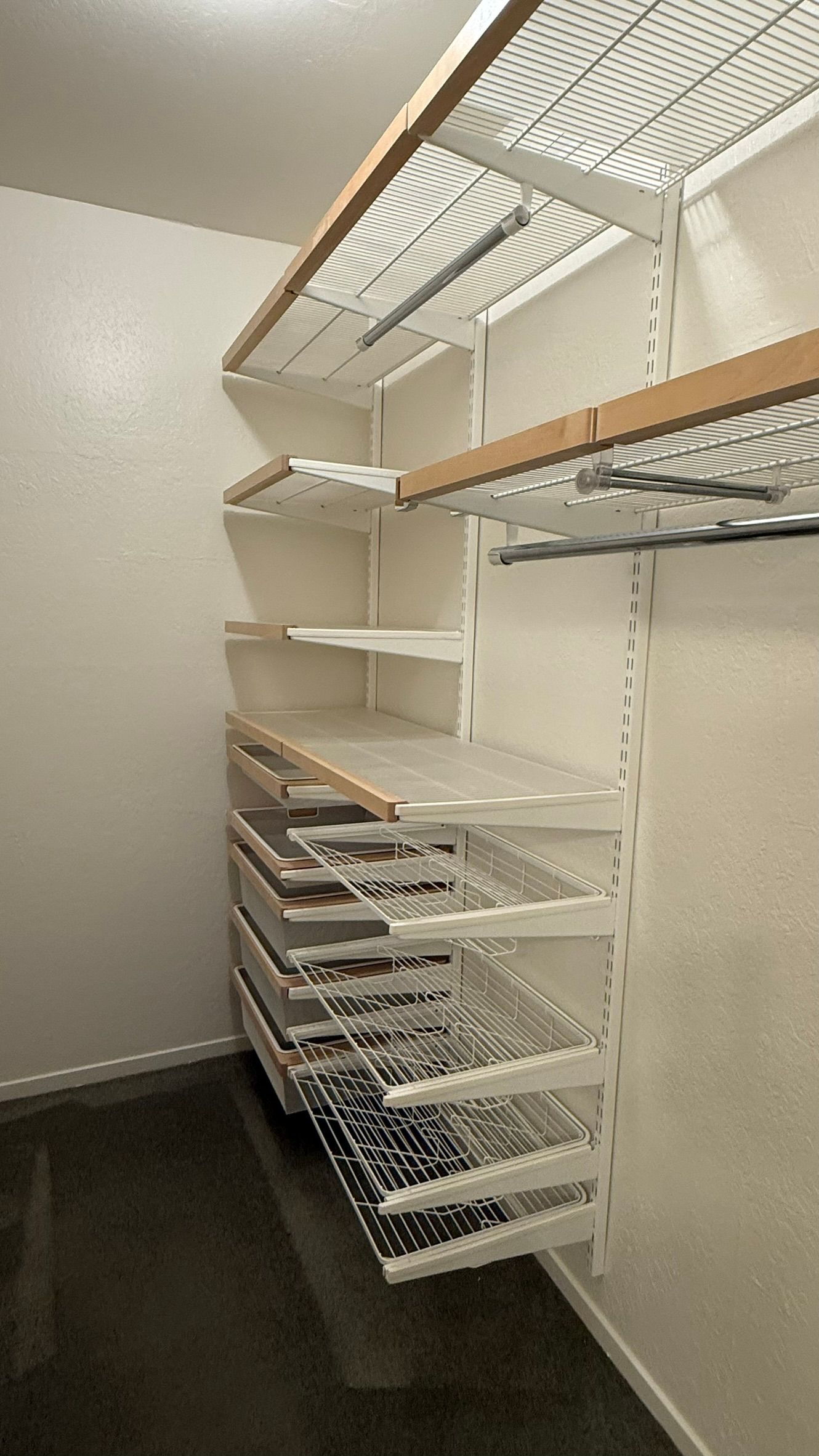 White closet shelving system with wire baskets, set against a white wall.