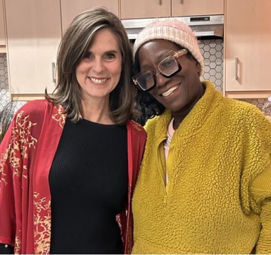 Two women are posing for a picture and one is wearing glasses