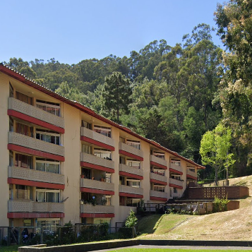 A large building with lots of balconies and trees in the background.