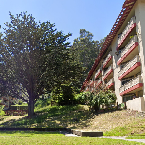 A large building with red balconies and a tree in front of it.