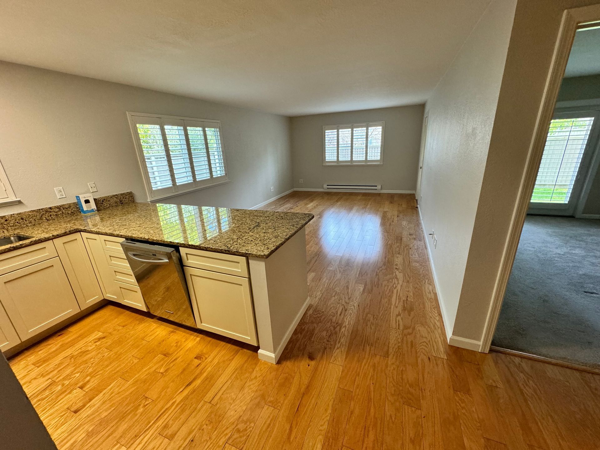 A kitchen with granite counter tops , stainless steel appliances , and hardwood floors.