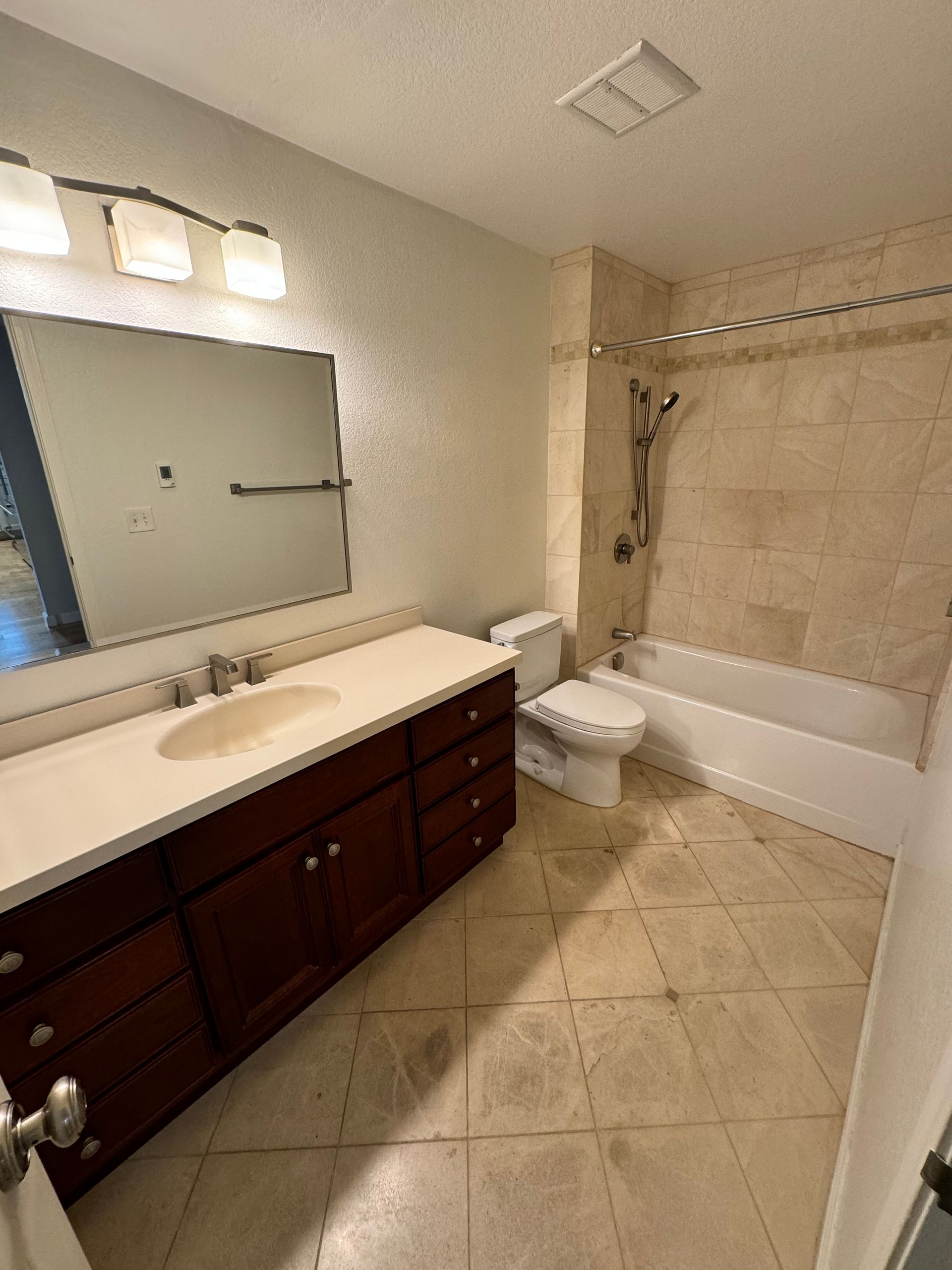 A bathroom with a sink , toilet , tub and mirror.