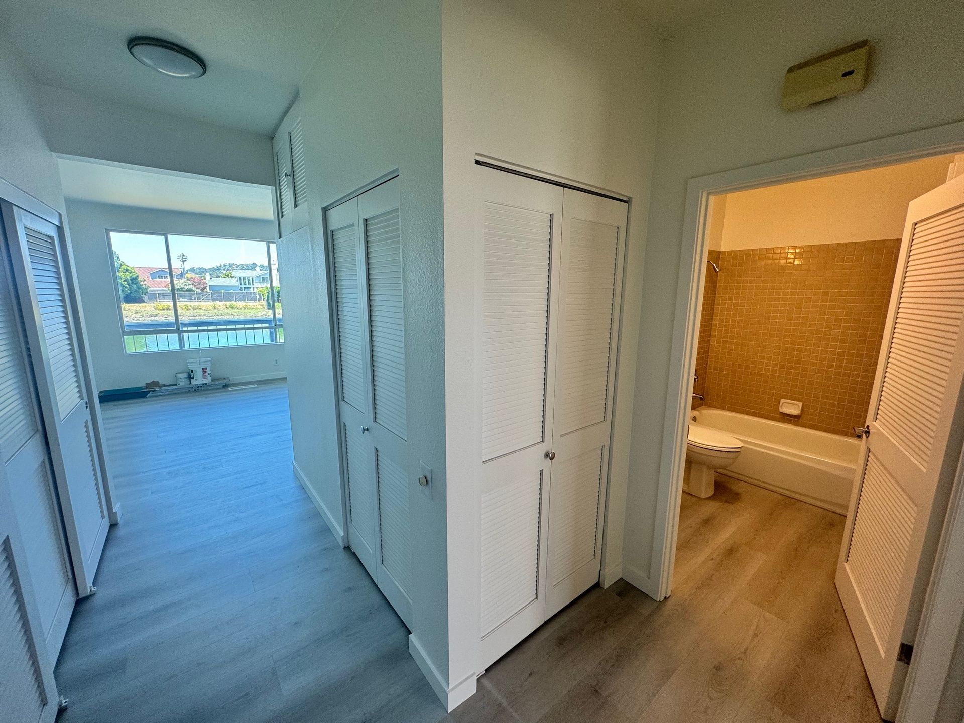A hallway leading to a bathroom and a bedroom in a house.