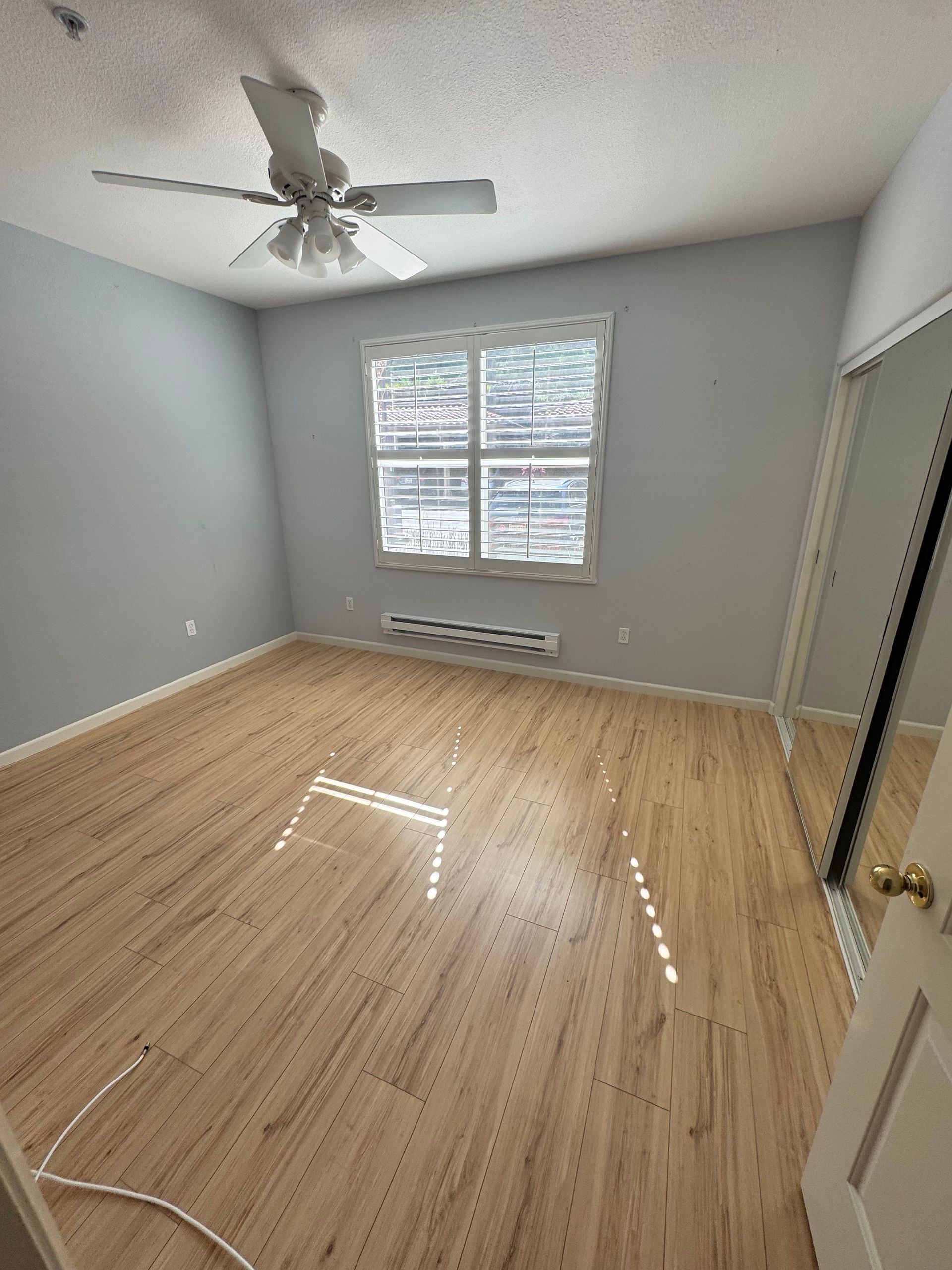 An empty bedroom with hardwood floors and a ceiling fan.