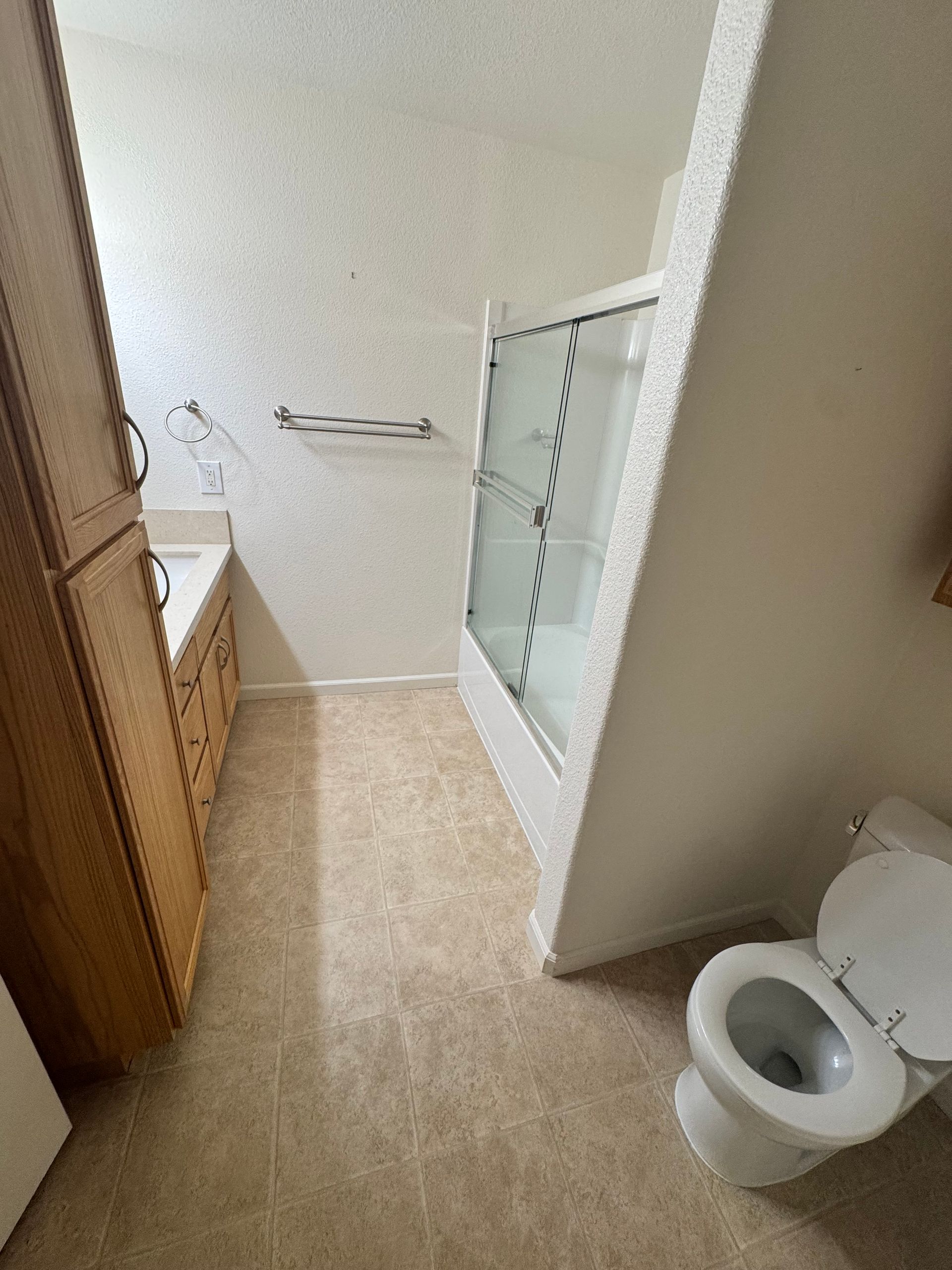 A bathroom with a toilet , sink and shower.