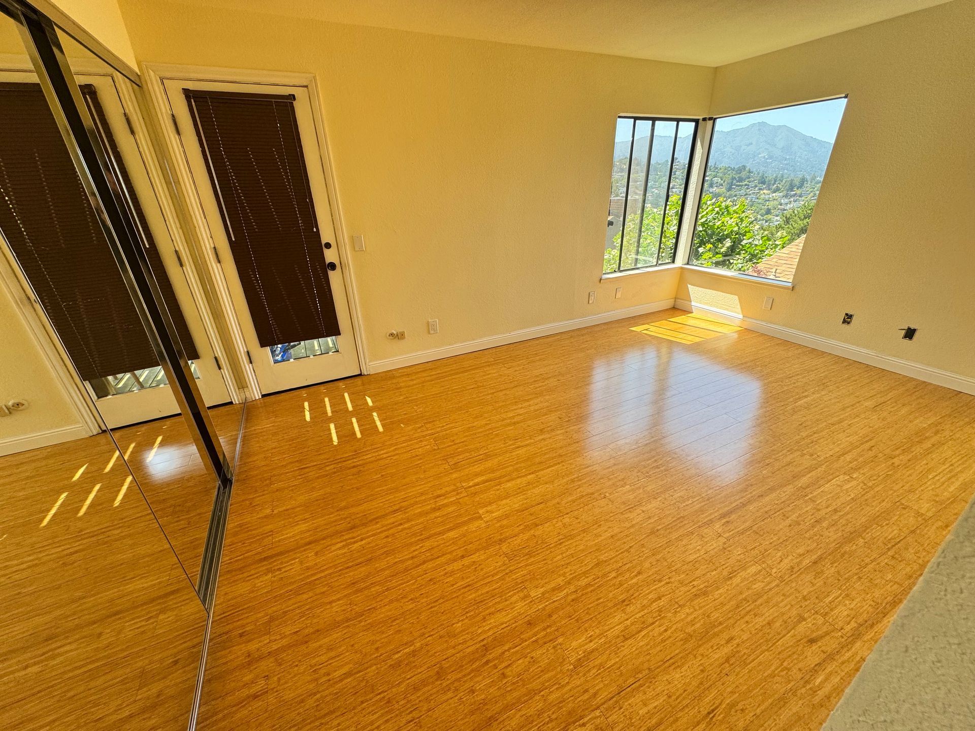 An empty room with hardwood floors and a large mirror.