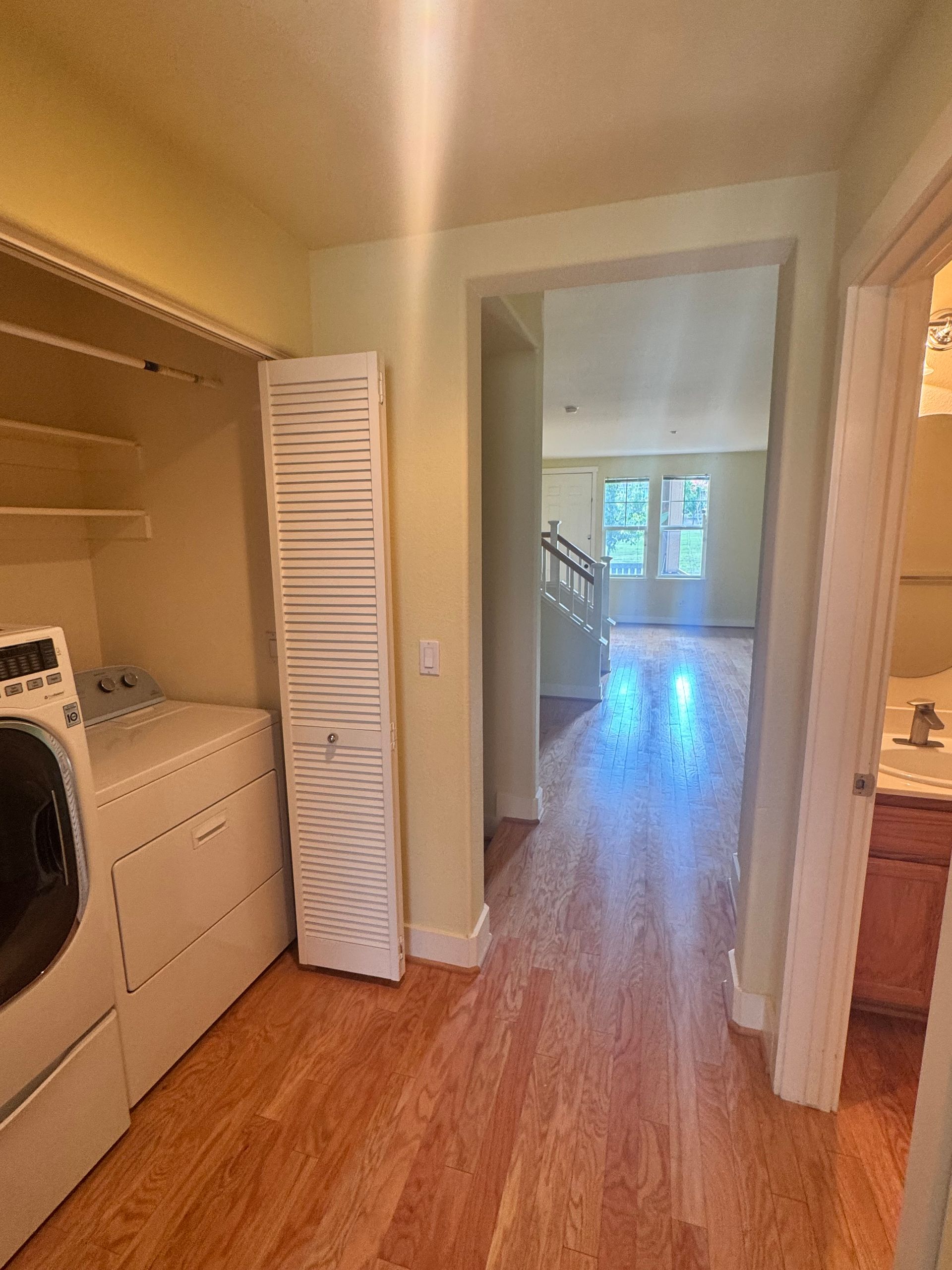 Laundry room with washer, dryer, closet, and hallway leading to living area.