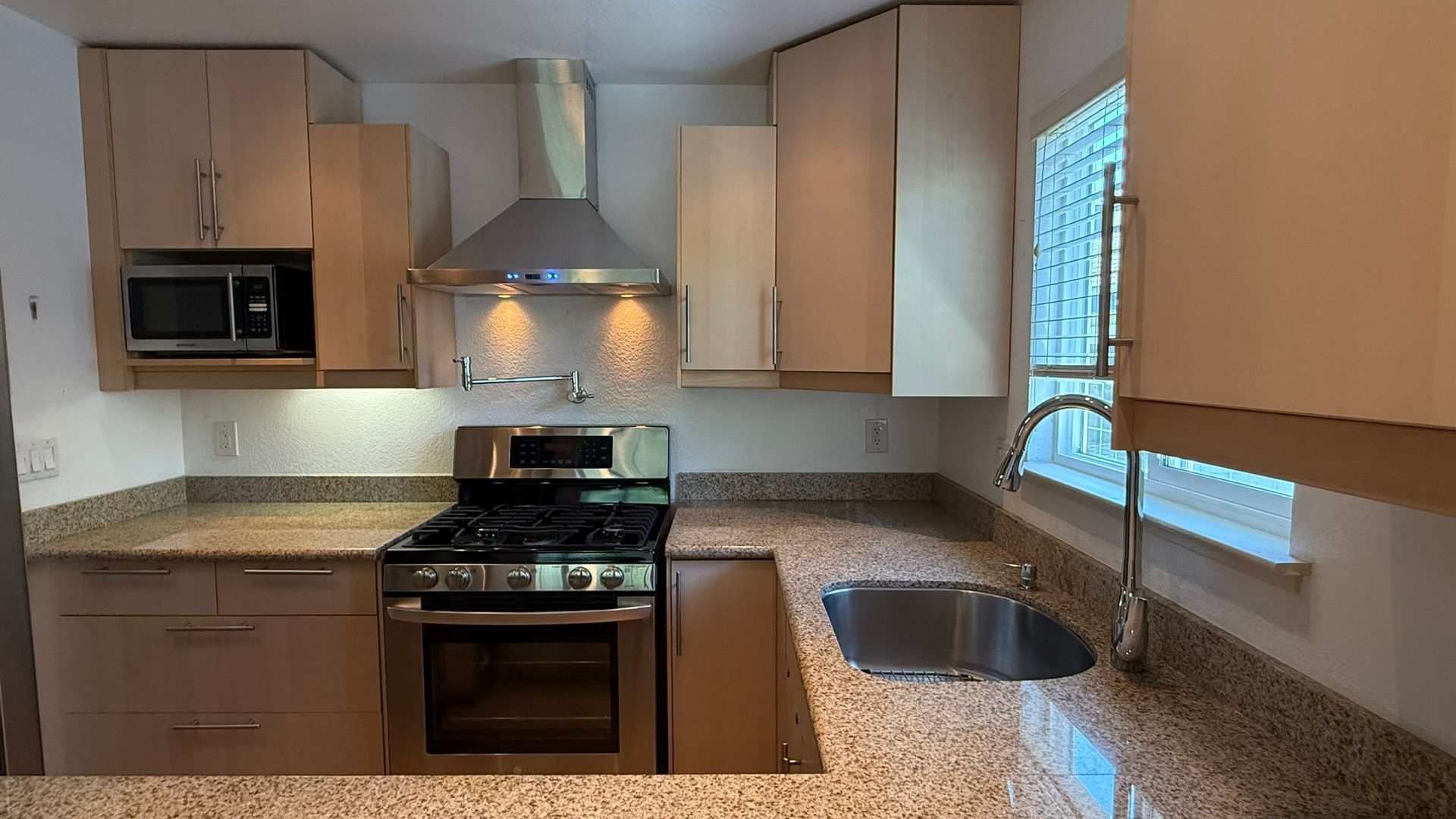 A kitchen with a stove , sink , and microwave.