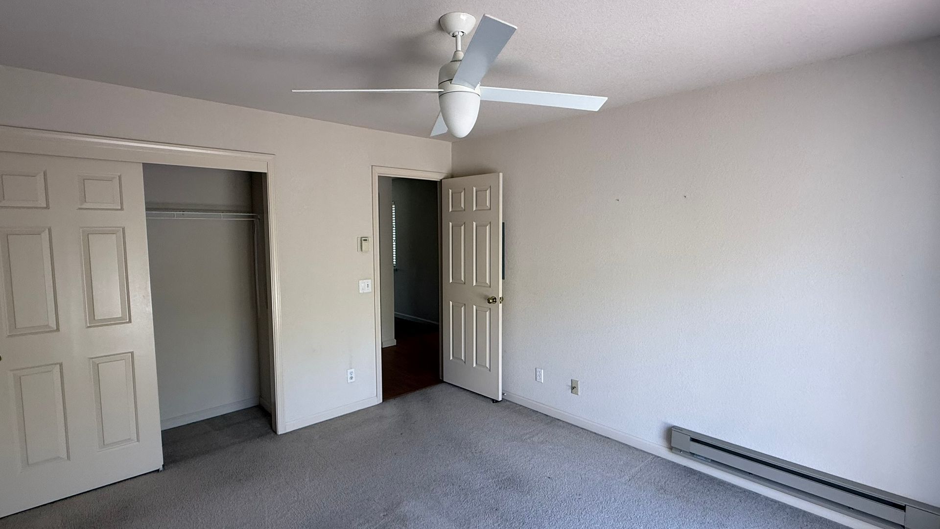An empty bedroom with a ceiling fan and a closet