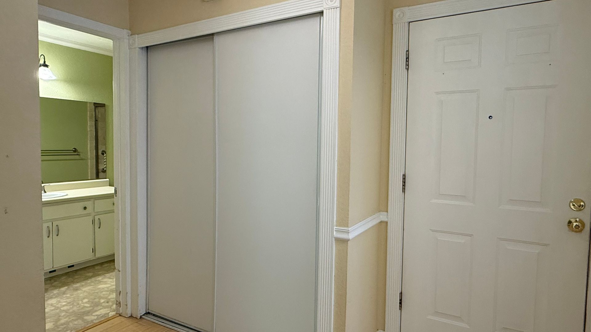 Hallway with closet and bathroom entrance; white door.