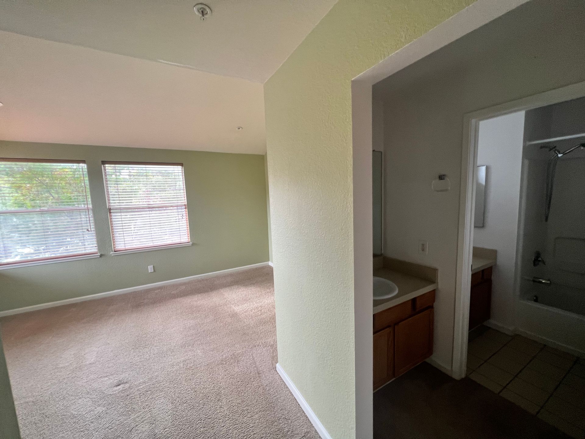 An empty room with a sink and a bathroom in the background.