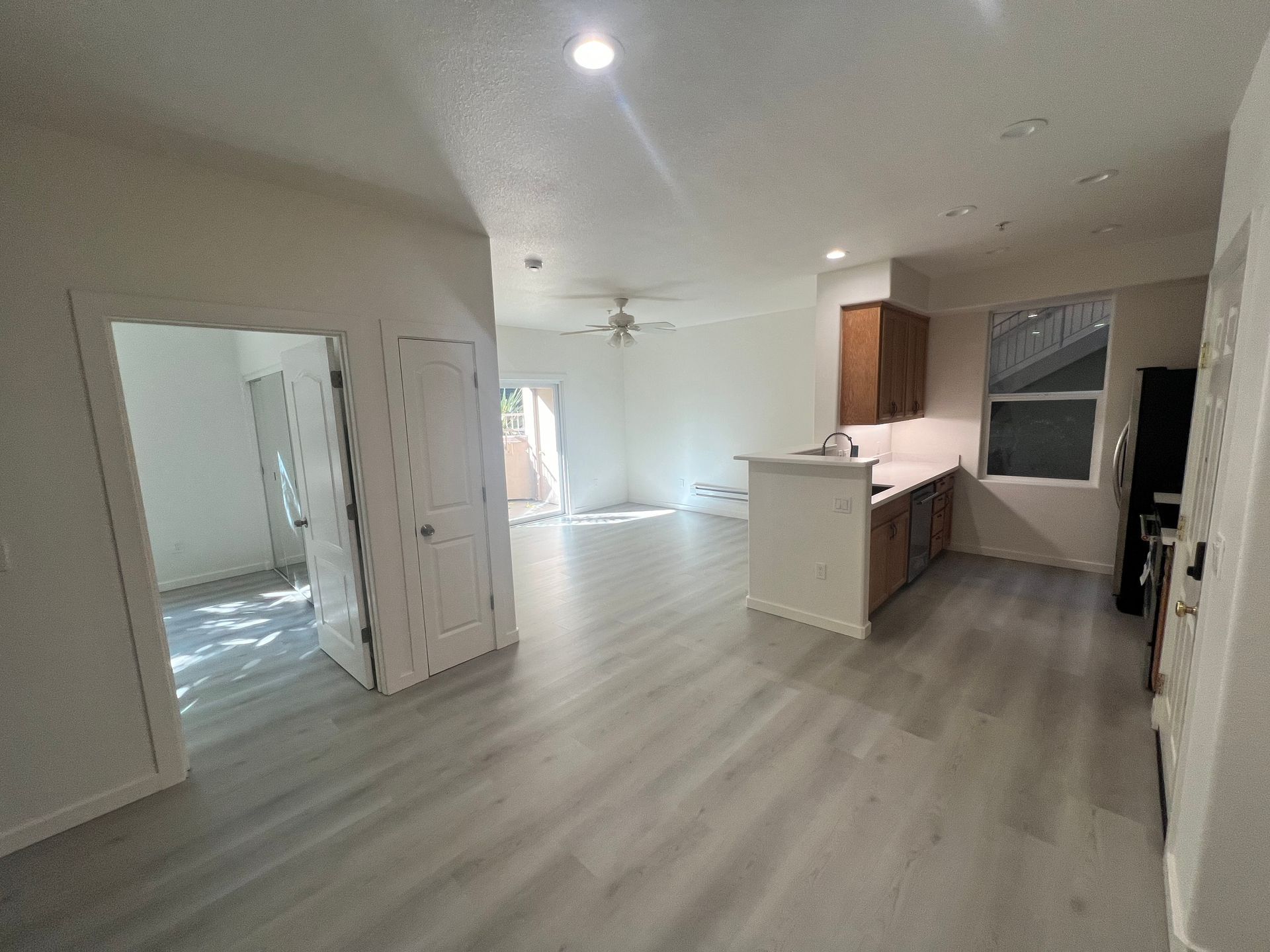 A living room with hardwood floors and a kitchen in a house.