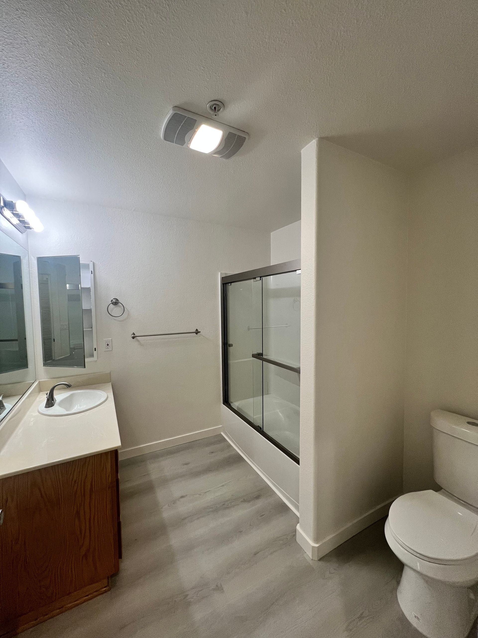 A bathroom with a toilet , sink and shower.