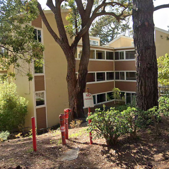 A large building with a lot of windows is surrounded by trees and bushes.